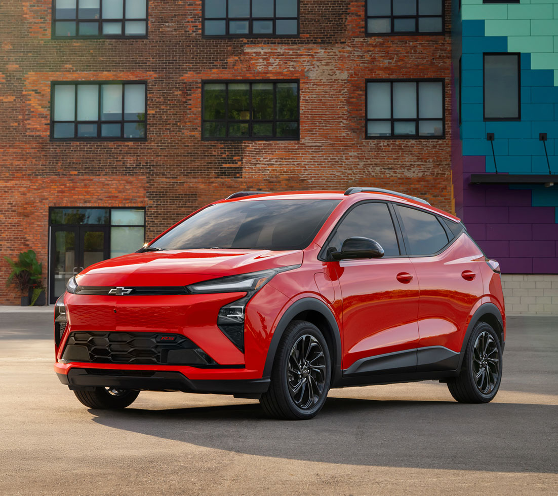 Red Chevrolet Bolt in an urban landscape featuring brick architecture and vibrant art