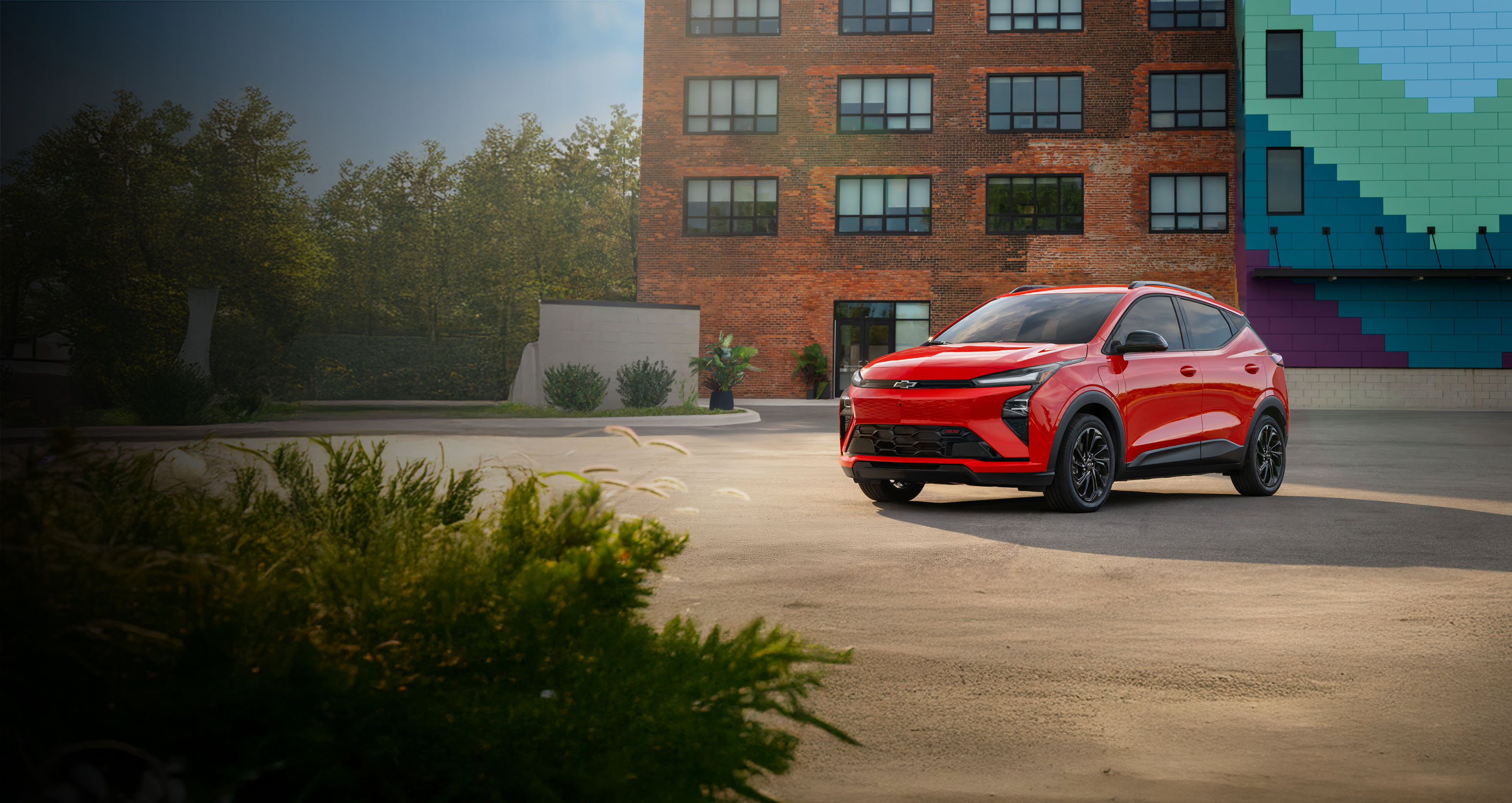 Red Chevrolet Bolt in an urban landscape featuring brick architecture and vibrant art