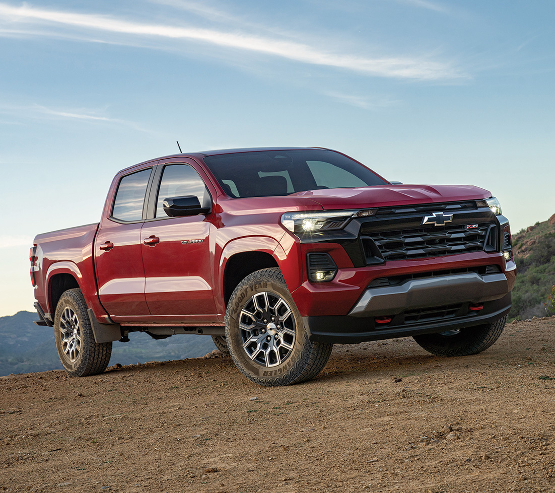 A red Chevrolet Colorado parked on a dirt path