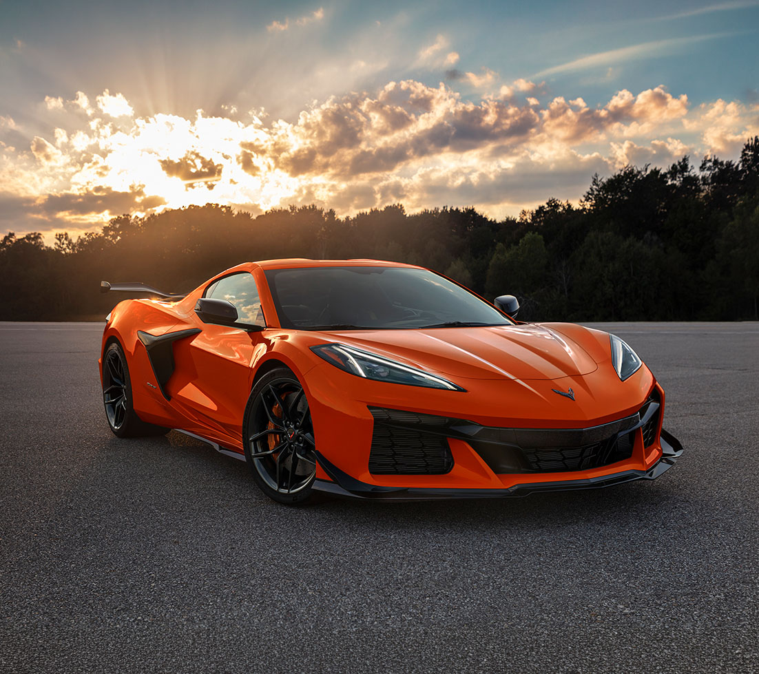 Vibrant orange Chevrolet Corvette in an asphalt lot at golden hour
