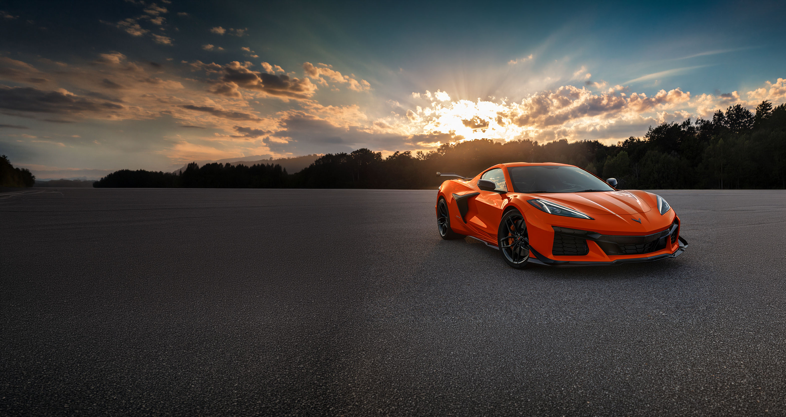 Vibrant orange Chevrolet Corvette in an asphalt lot at golden hour